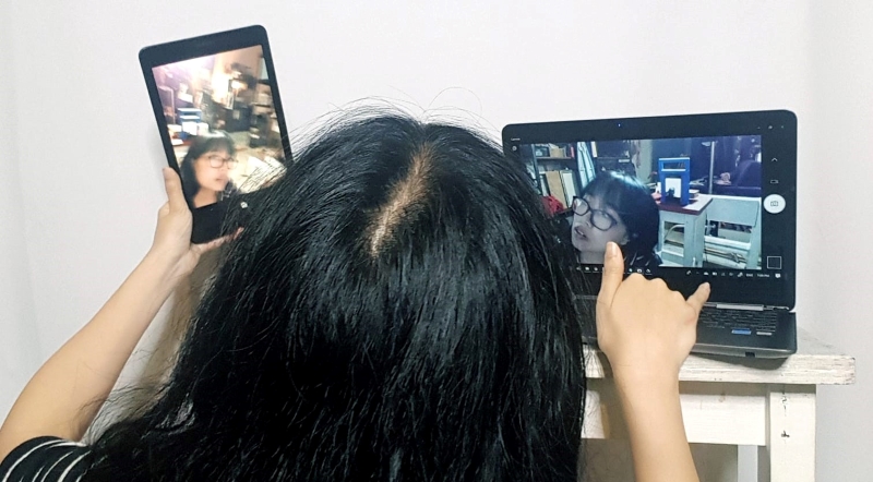 Person taking selfies at the same time on a smartphone and on a laptop.